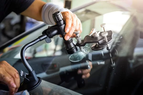 Technicien réparant un impact sur pare-brise